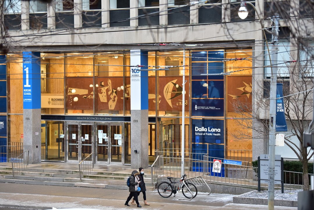 A single blue disposable surgical mask is laid carefully on top of some irregularly stacked newsletters, the papers having...